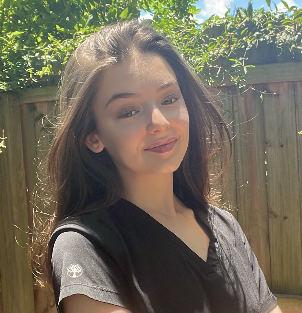 Emmie Stone in a black top in front of a fence