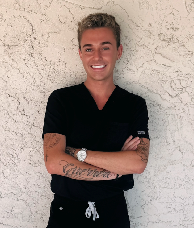 Sebastian Childress in black scrubs leaning against a wall